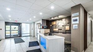A hotel reception area with a check-in counter, a digital screen, and a sign indicating check-in times. - Holiday Inn Express Flint-Campus Area by IHG (Flint)