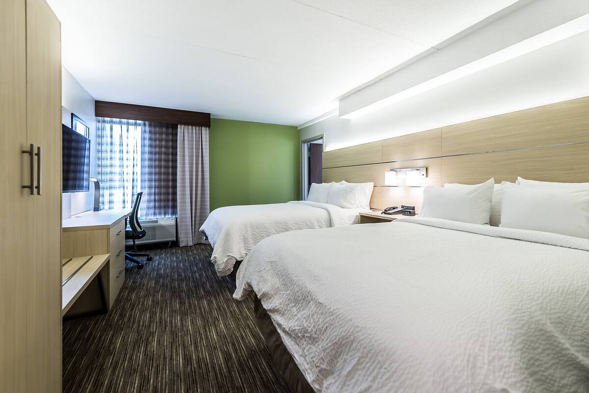 Une chambre d’hôtel avec deux lits, un bureau et une chaise.