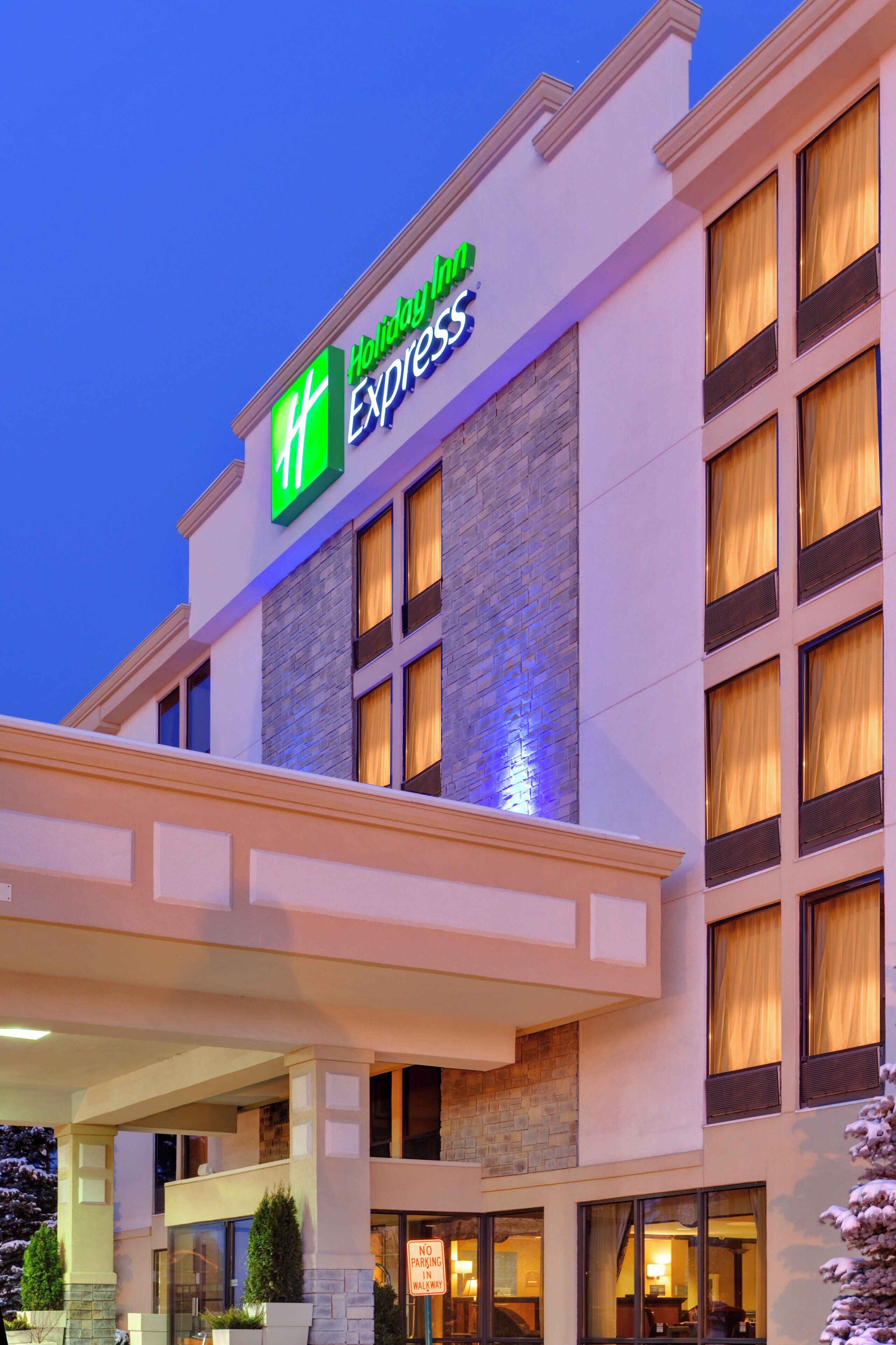 A Holiday Inn Express hotel with a prominent green and white sign, multiple windows with curtains, and a stone facade.