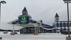 A Quality Inn by Choice Hotels with a distinctive blue and white color scheme, a covered entrance, and a snow-covered parking lot. - Quality Inn Gaylord (Gaylord)