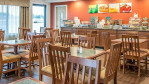 A breakfast area with wooden tables and chairs, a coffee station, and a wall with food images. - Quality Inn Gaylord (Gaylord)