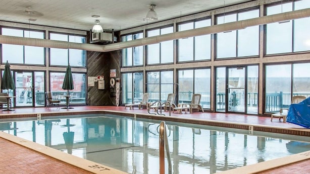 An indoor swimming pool with clear glass walls, a tiled floor, and a few lounge chairs. - Quality Inn Gaylord (Gaylord)