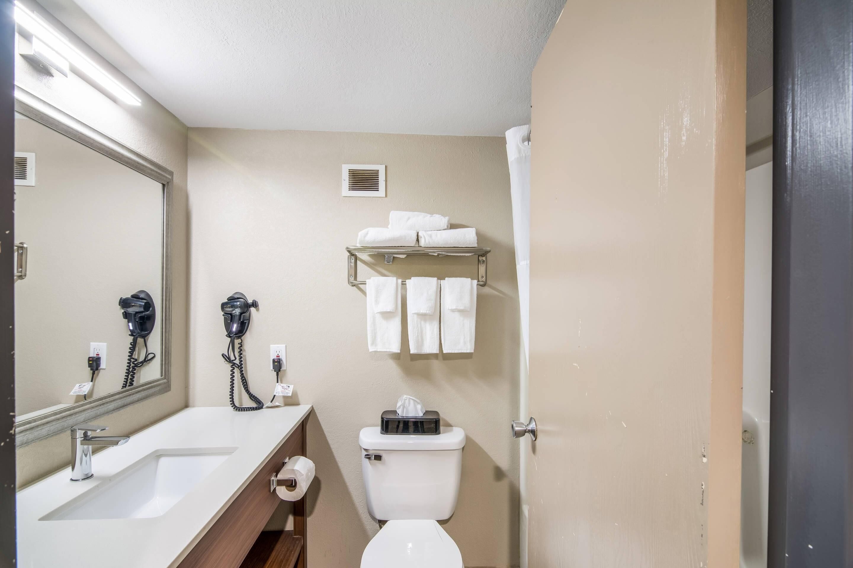 Un baño con lavamanos, inodoro, toallero y espejo.