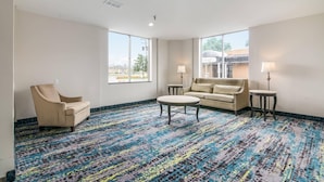 A hotel room with a patterned carpet, a sofa, a chair, and two lamps. - Quality Inn Rochester West (Rochester)