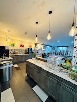 Cocina moderna con encimeras de granito, electrodomésticos de acero inoxidable e iluminación colgante.