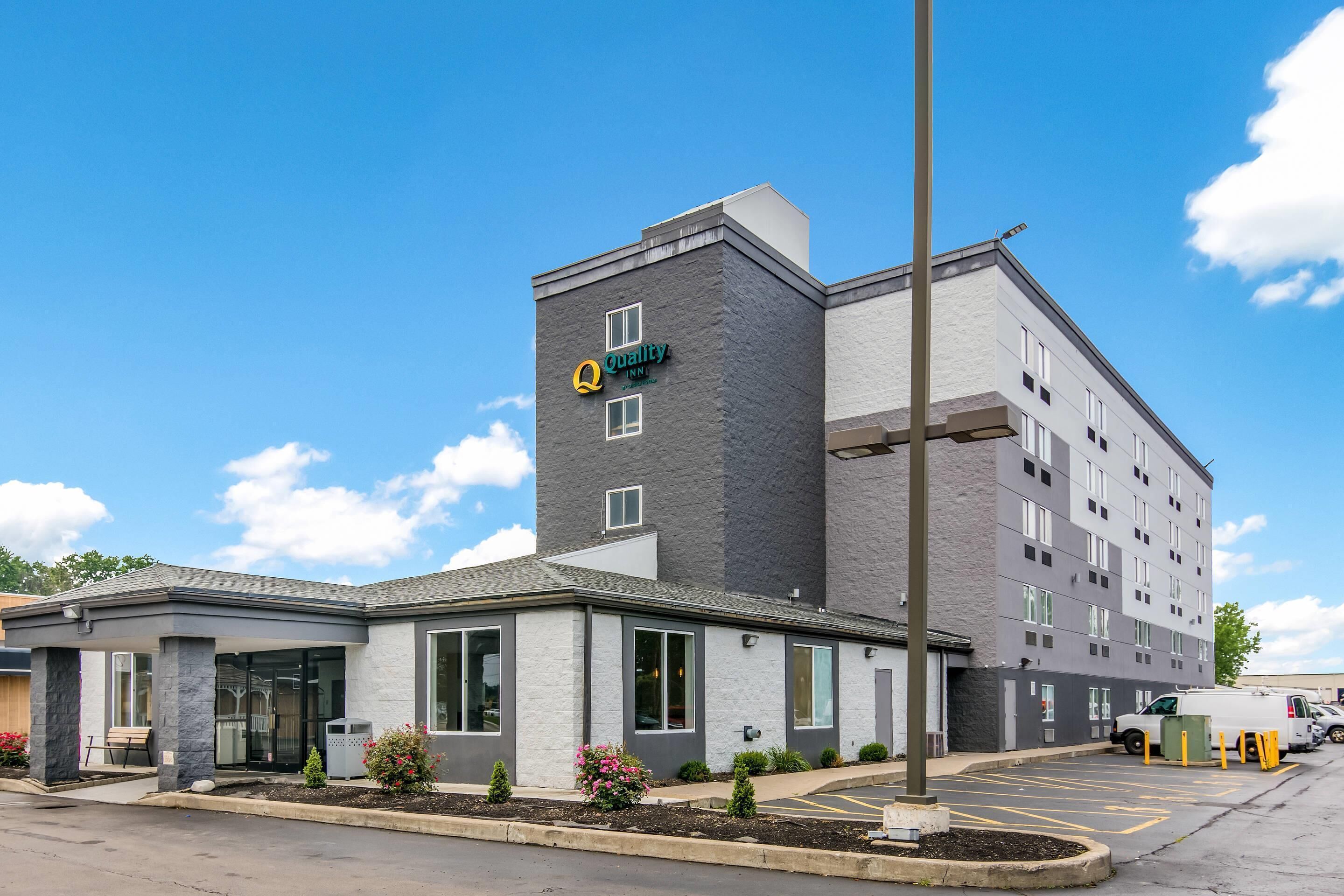 A hotel with a modern design, featuring a prominent sign, a covered entrance, and a parking area.