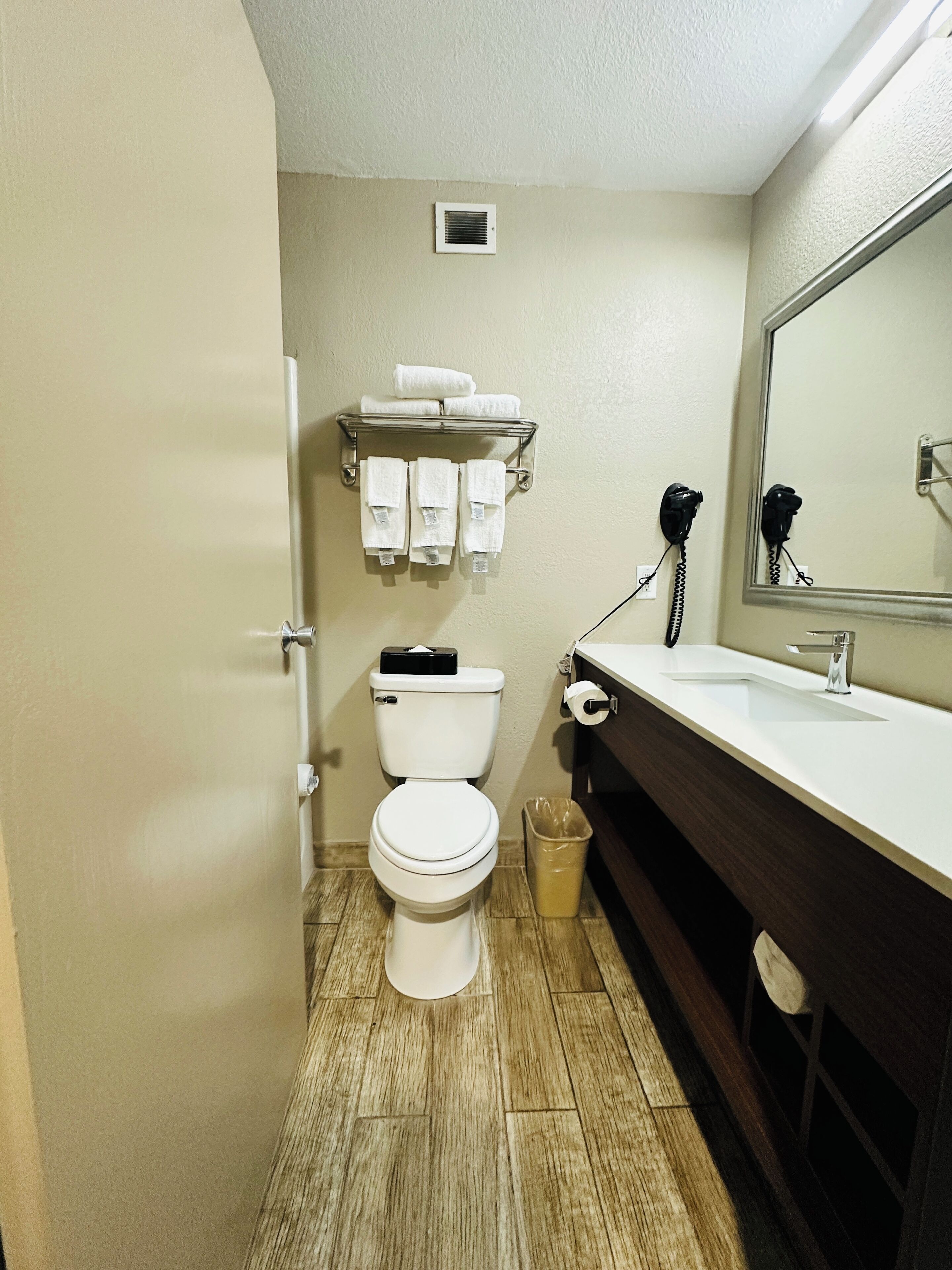 A compact bathroom with a toilet, sink, and a mirror.