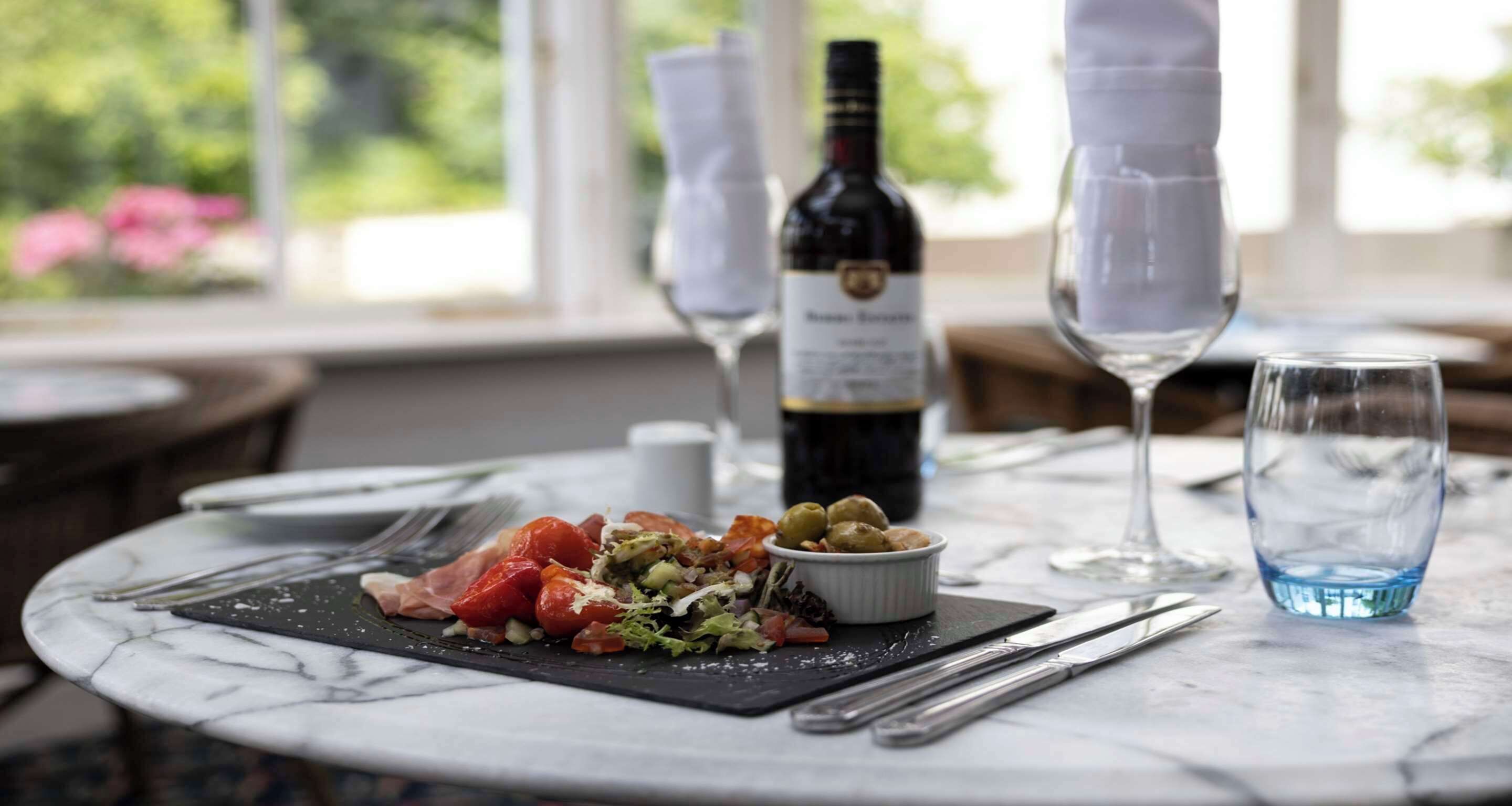 A dining table with a meal, a bottle of wine, and glasses.