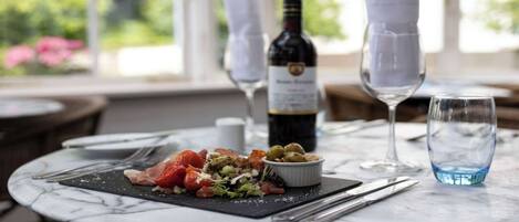 A dining table with a meal, a bottle of wine, and glasses.