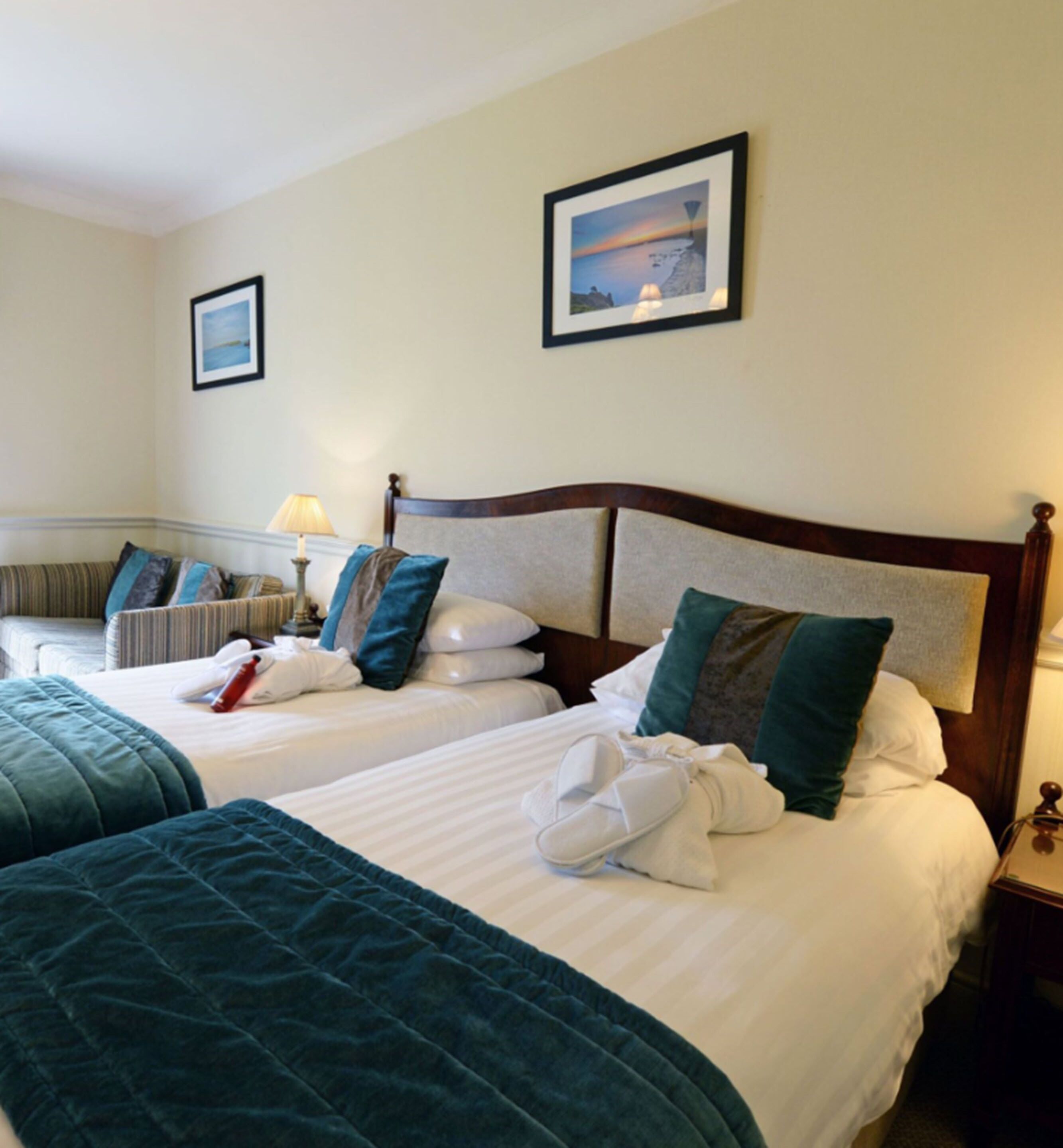 A hotel room with two beds, a view of the sea, and a framed picture on the wall.