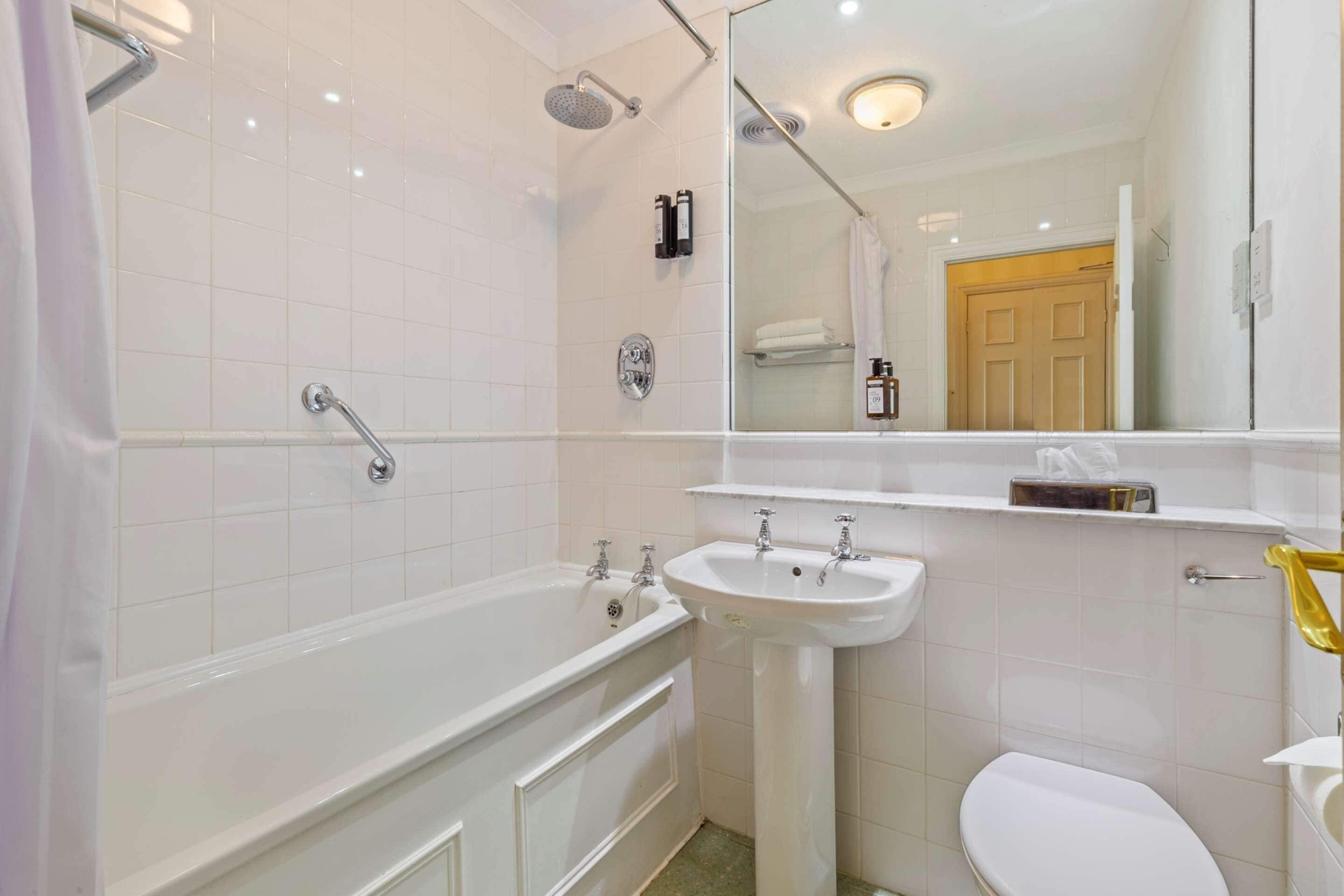 A modern bathroom with a bathtub, sink, and toilet.