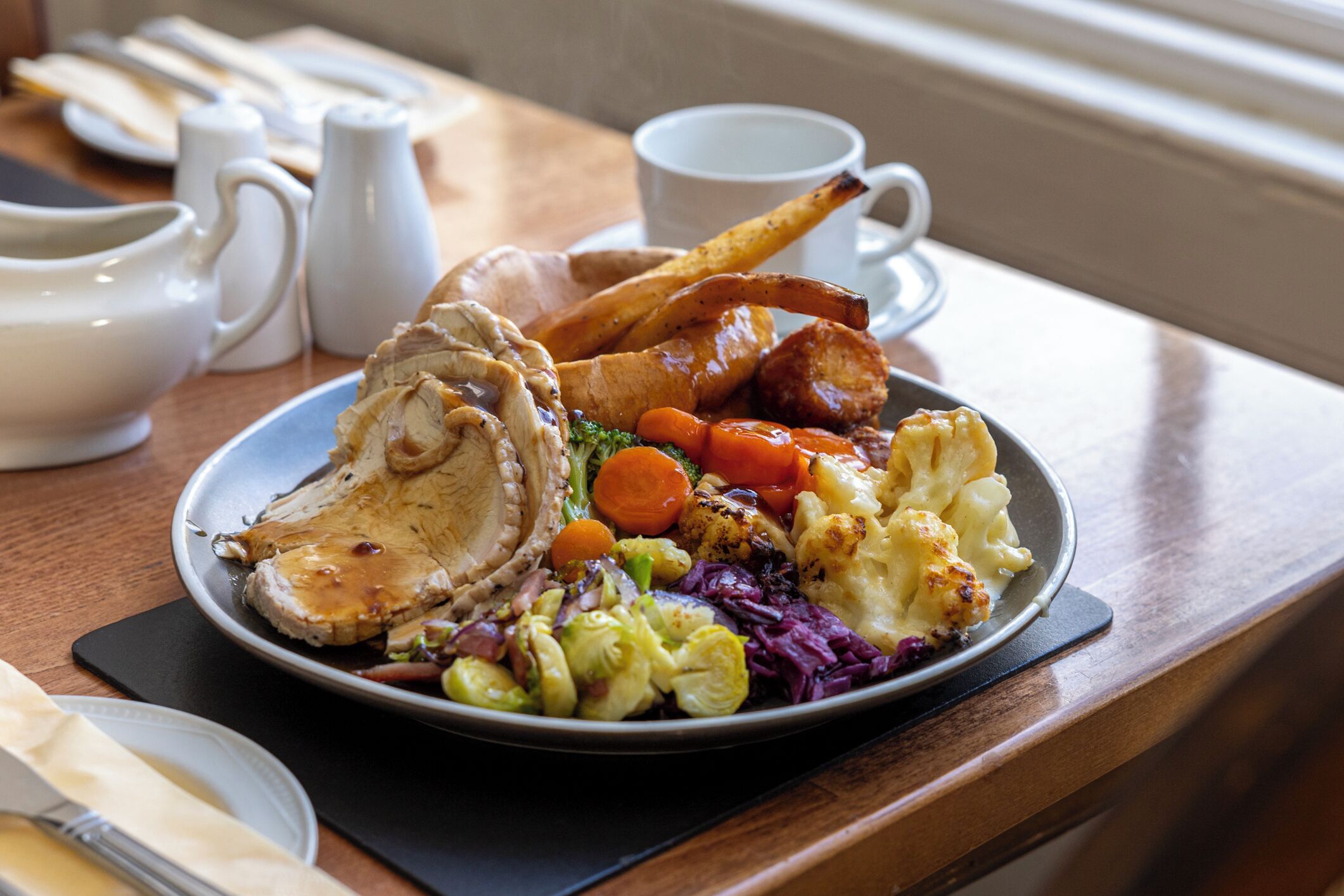 A plate of food with roasted meat, vegetables, and gravy.