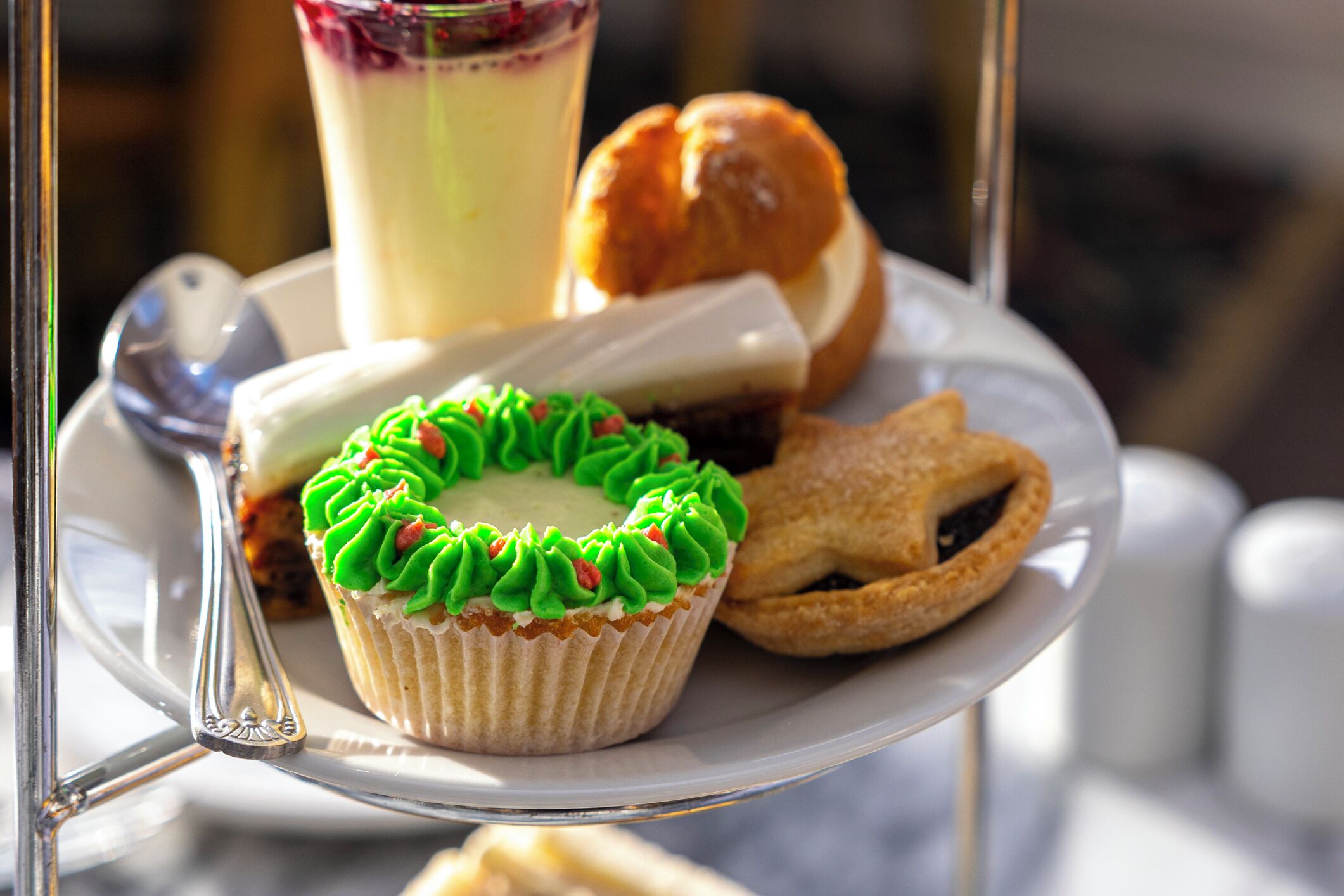 Un plateau de desserts comprenant un cupcake, une tarte et une boisson, le tout présenté sur un présentoir en verre.