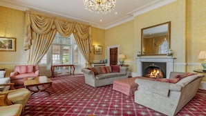 A traditional room with a fireplace, patterned carpet, and classic furniture. - Best Western Lamphey Court Hotel & Spa (Pembroke)