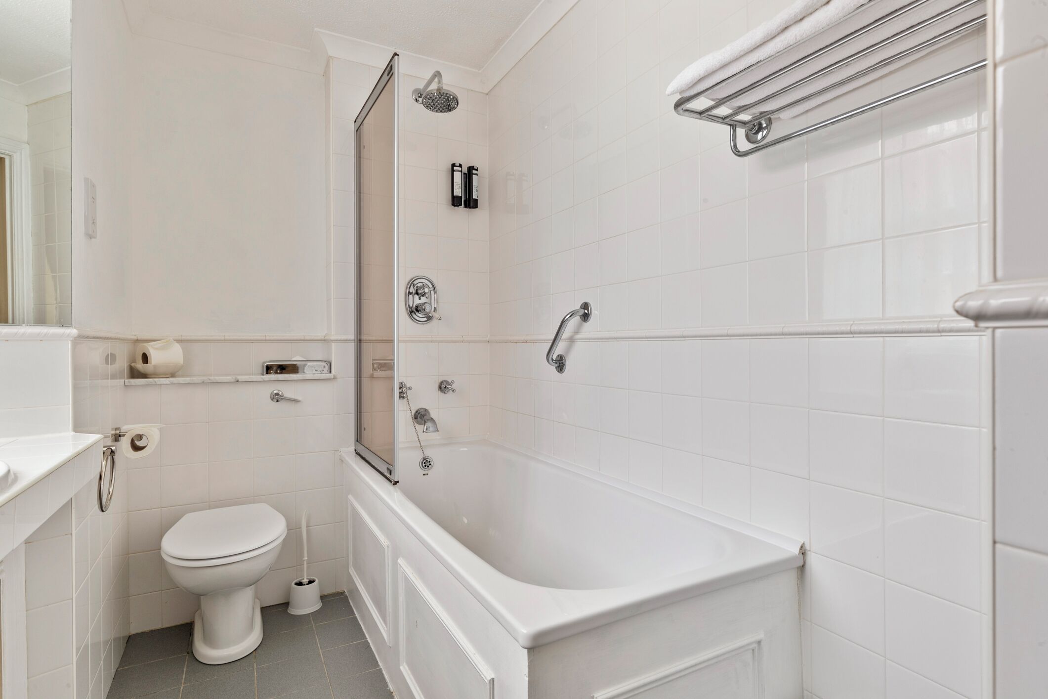A modern bathroom with a white toilet, a bathtub, and a shower area.