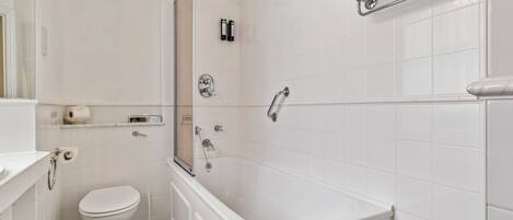 A modern bathroom with a white toilet, a bathtub, and a shower area.