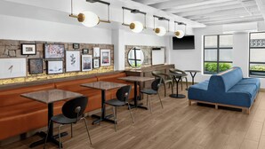 A modern interior with a stone wall, framed artwork, a blue sofa, and a wooden floor. - ARC Hotel, Washington DC, Series by Marriott (Washington)