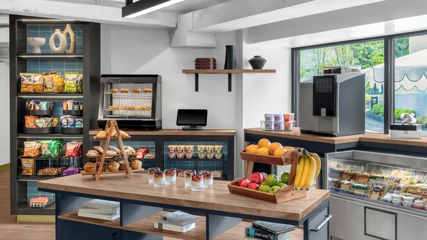 A bakery counter with pastries, a display of packaged snacks, and a refrigerated section with dairy products. - ARC Hotel, Washington DC, Series by Marriott (Washington)