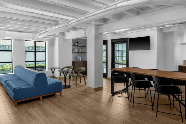 A modern interior with a blue sofa, wooden tables, and a long dining table with chairs.