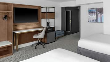 A hotel room with a desk, chair, bed, and a small kitchenette.