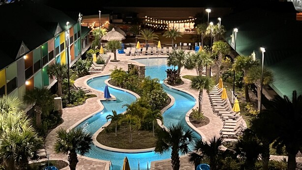 A resort pool area with a winding pool, lounge chairs, and umbrellas. - Beachside Hotel & Suites Cocoa Beach - Port Canaveral (Cocoa Beach)