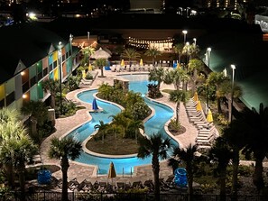 A resort pool area with a winding pool, lounge chairs, and umbrellas. - Beachside Hotel & Suites Cocoa Beach - Port Canaveral (Cocoa Beach)