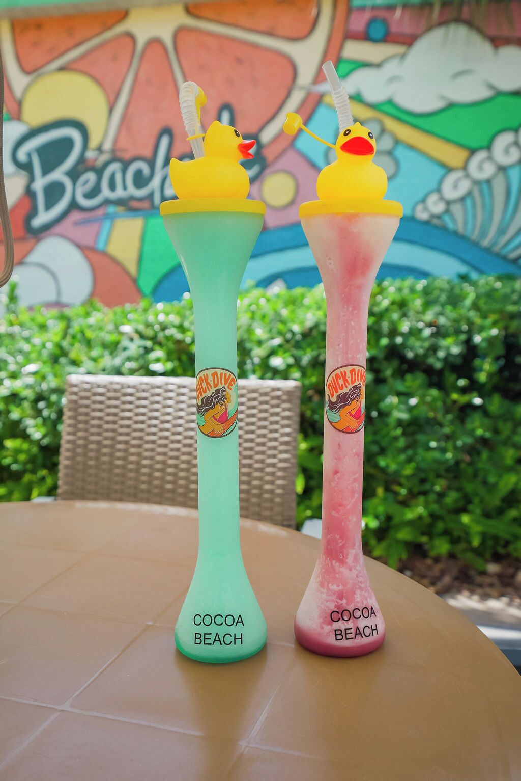 Two colorful drinks labeled 'Cocoa Beach' with a beach-themed mural in the background.