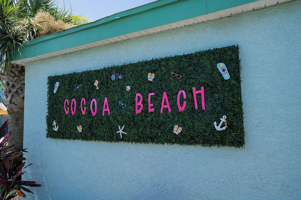 A wall with the text "COCOA BEACH" surrounded by small decorative items like sunglasses, flip-flops, and a star.