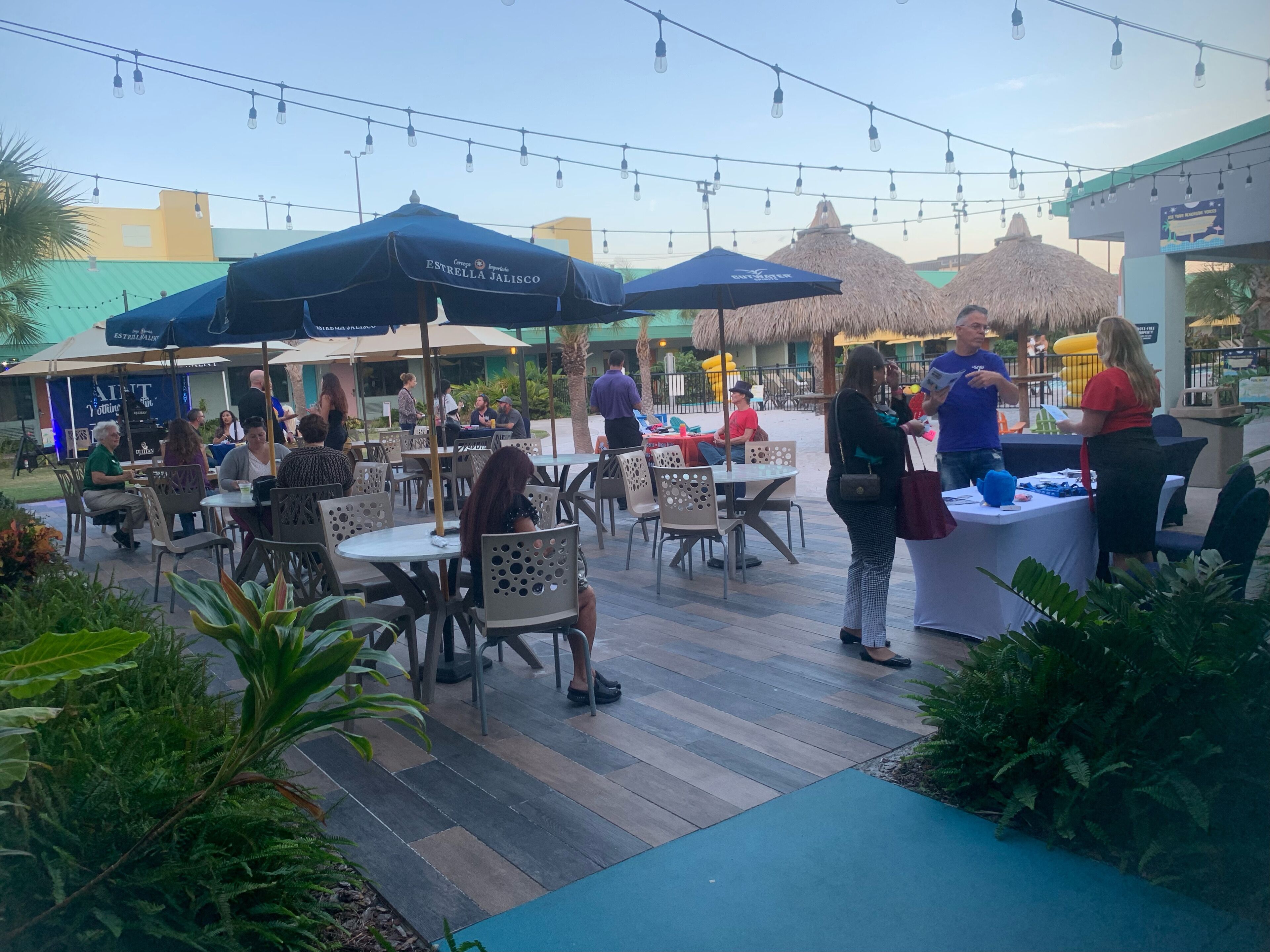 An outdoor dining area with tables and chairs, umbrellas, and string lights.