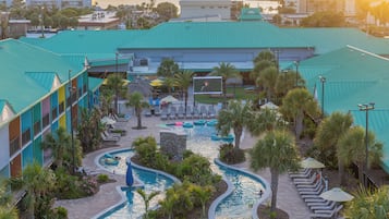 A resort with a swimming pool, lounge chairs, and a view of the water.