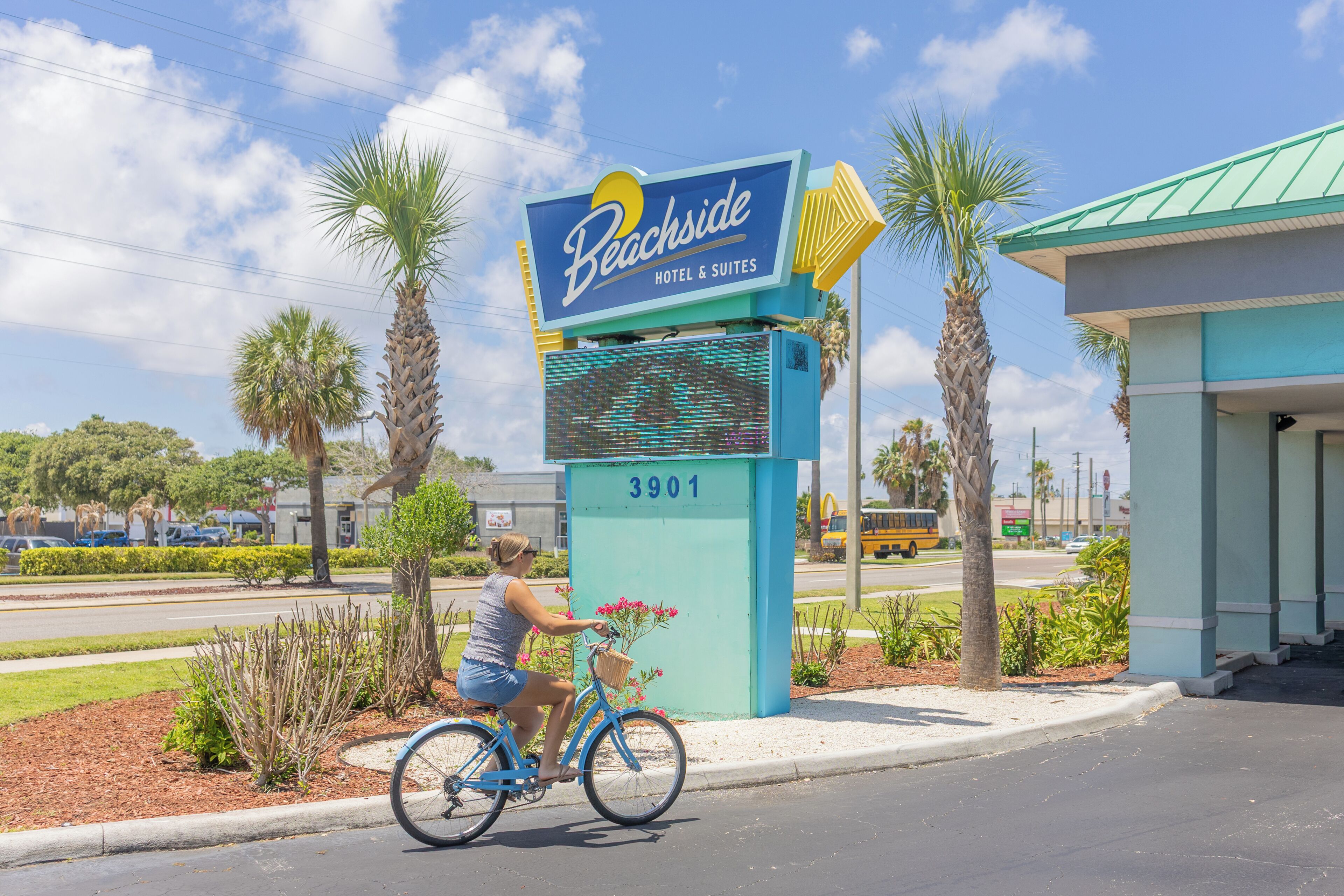 Schild des Beachside Hotel & Suites mit der Nummer 3901, ein Fahrrad mit Korb und Palmen im Hintergrund.