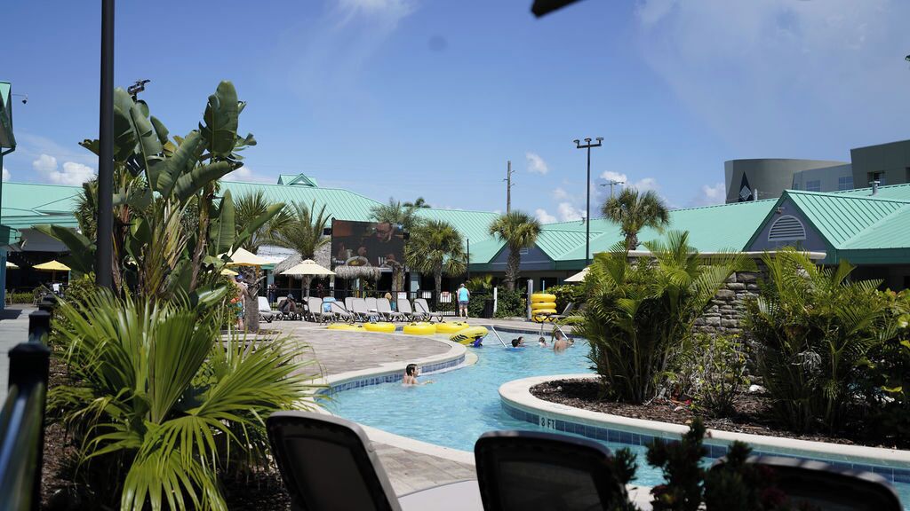 Ein Schwimmbeckenbereich mit Liegestühlen, Sonnenschirmen und einem tropischen Garten.