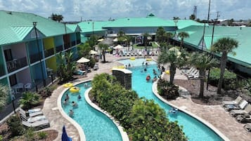 A hotel with a large outdoor pool area, multiple swimming pools, and lounge chairs.