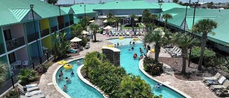A hotel with a large outdoor pool area, multiple swimming pools, and lounge chairs.