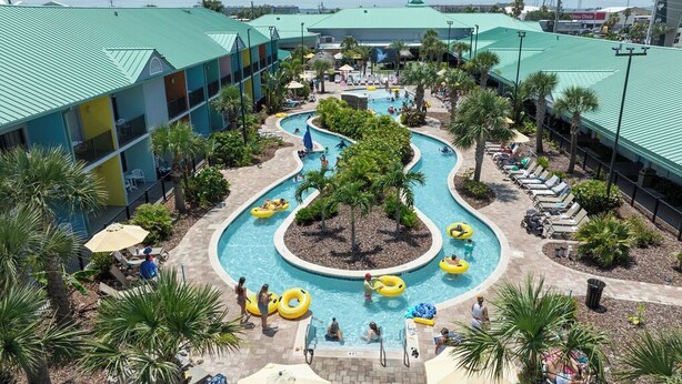 Un resort con un área de piscina central, múltiples piscinas y un edificio con techo verde.