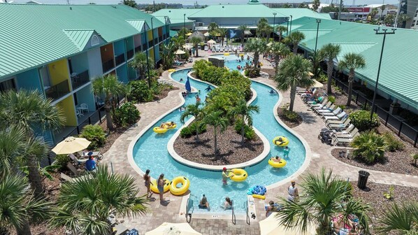 Ein Resort mit einem zentralen Poolbereich, mehreren Schwimmbecken und einem Gebäude mit begrüntem Dach.