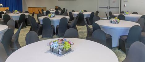 A conference room with round tables, chairs, and a projector screen.