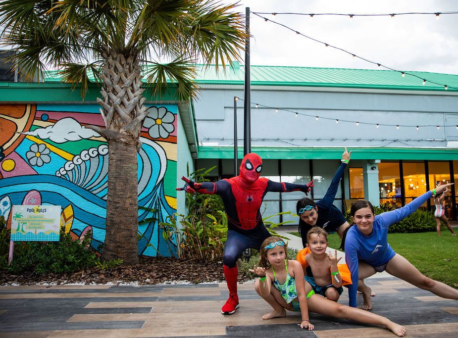 A mural with a pool rules sign, palm trees, and a building with a green roof.