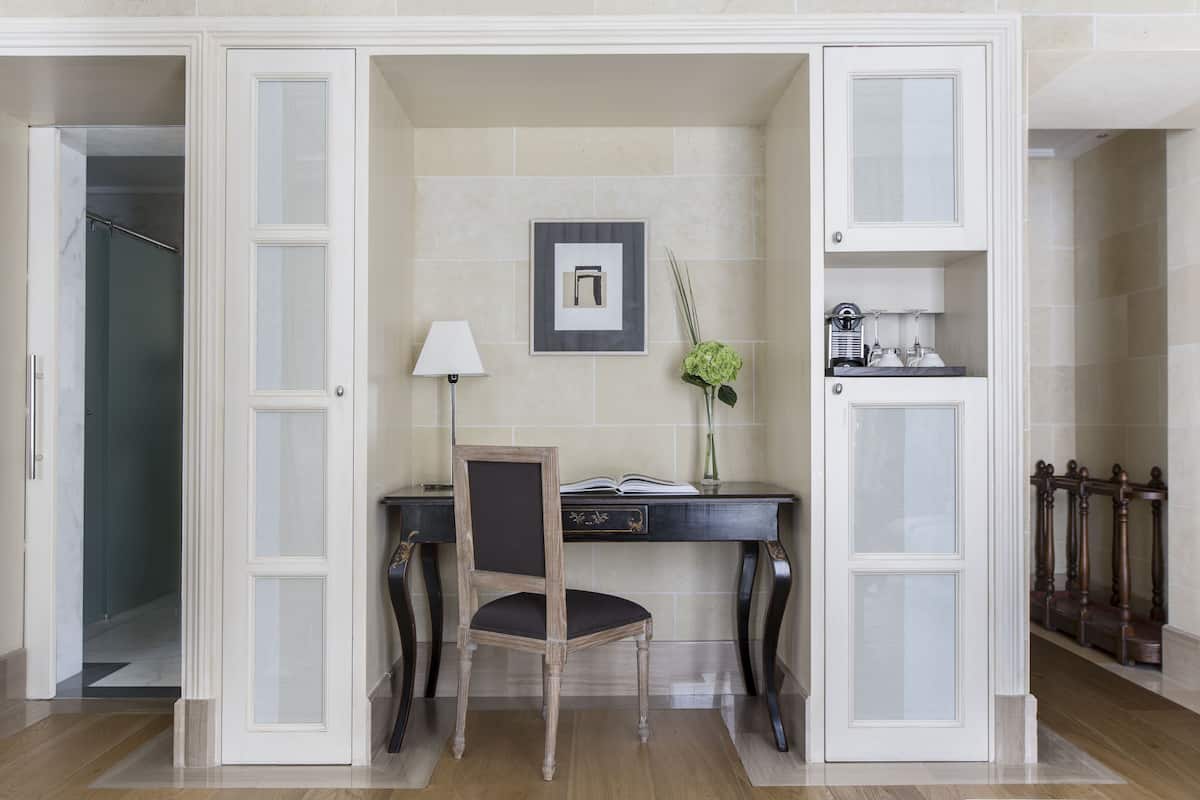 A study with a desk, chair, lamp, and framed picture on the wall.