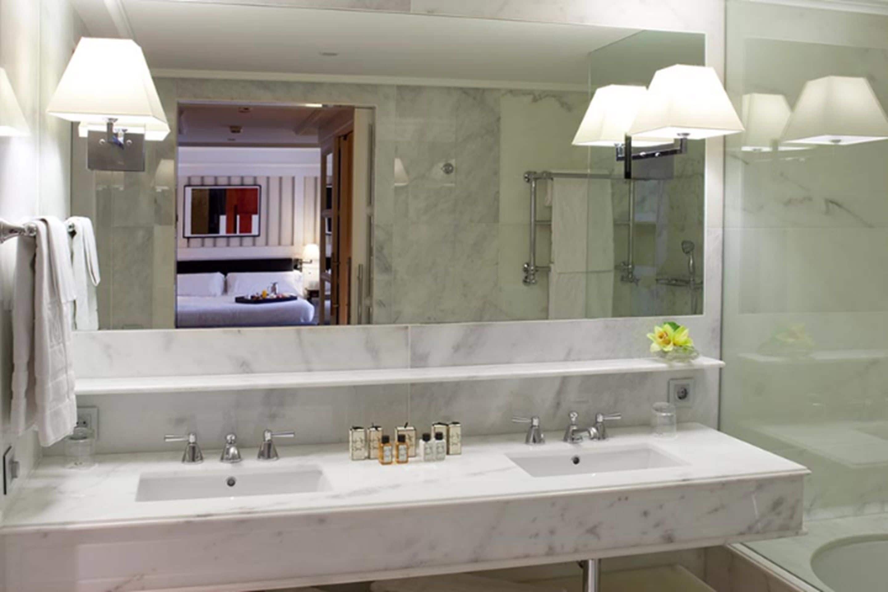 Un bagno moderno con uno specchio grande, due lavabi e una zona doccia.
