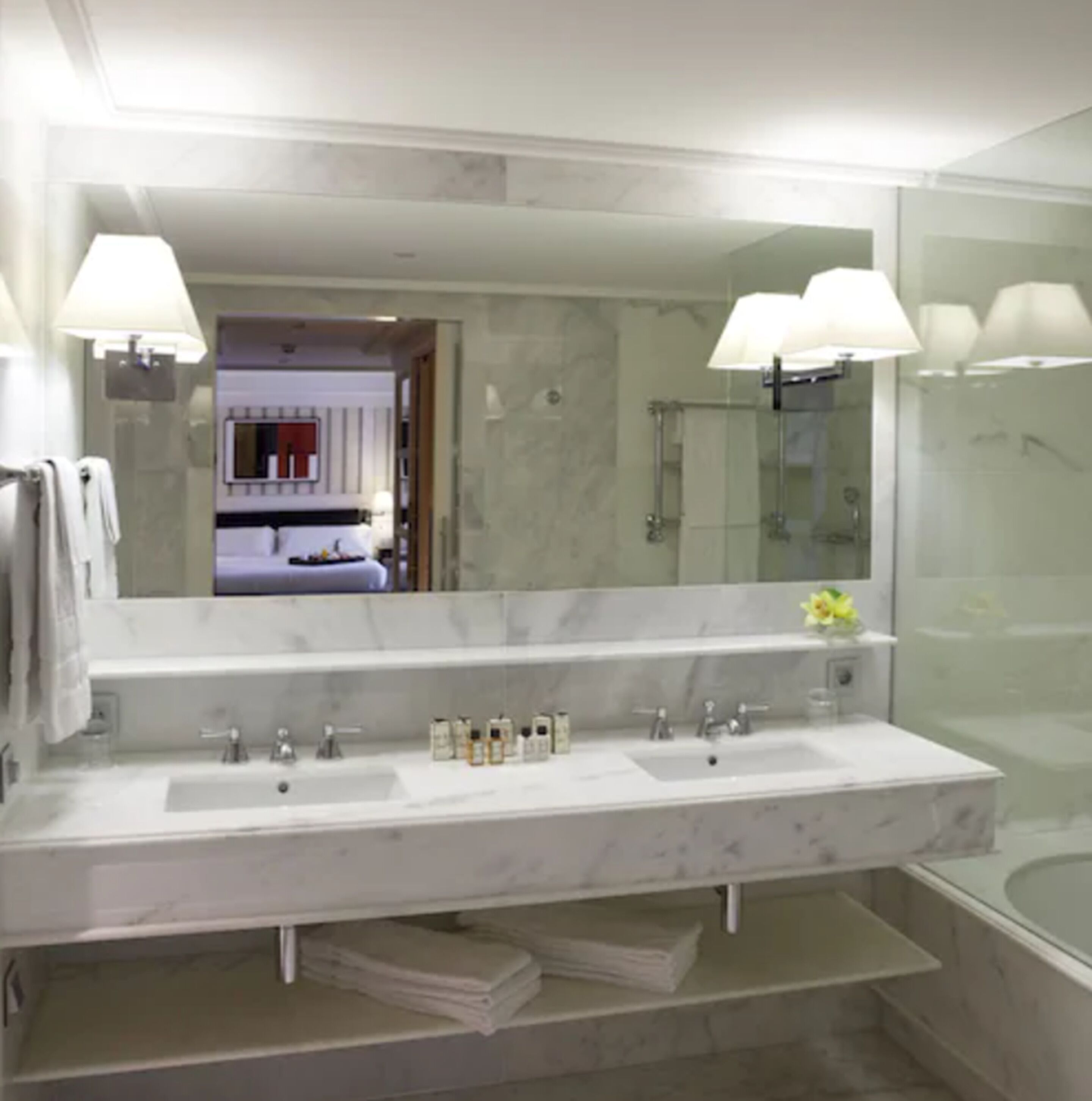 Un baño moderno con un espejo grande, dos lavamanos y una zona de ducha.
