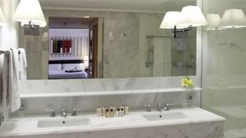 Un baño moderno con un espejo grande, dos lavamanos y una zona de ducha.