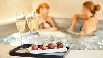 A tray with two glasses of champagne and chocolate-covered strawberries on a marble surface.