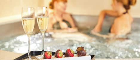 Una bandeja con dos copas de champán y fresas cubiertas de chocolate sobre una superficie de mármol.