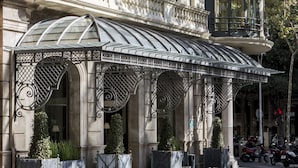 Eine prachtvolle Hotelfassade mit aufwendigen Balkonen, einem überdachten Eingang und mehreren Flaggen.