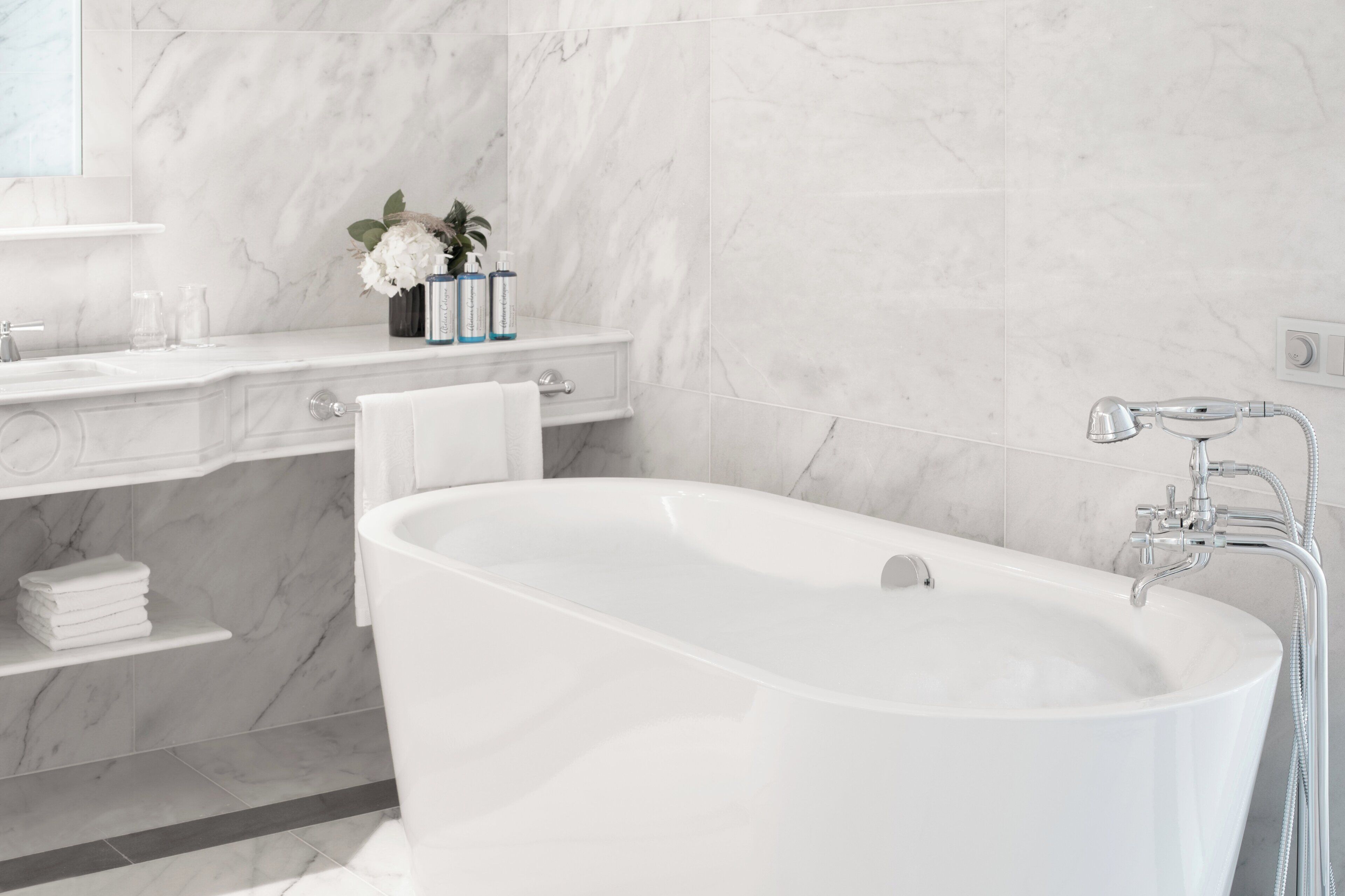 Un baño moderno con una bañera independiente, un tocador con espejo y un estante con artículos de aseo.