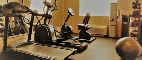 A gym with treadmills, stationary bikes, and a mirrored wall.