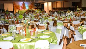 Un salón de banquetes con mesas redondas dispuestas para un evento formal, que incluye manteles, sillas y centros de mesa.