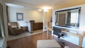 Un espacio habitable compacto con kitchenette, comedor y zona de estar con sofá y sillones.