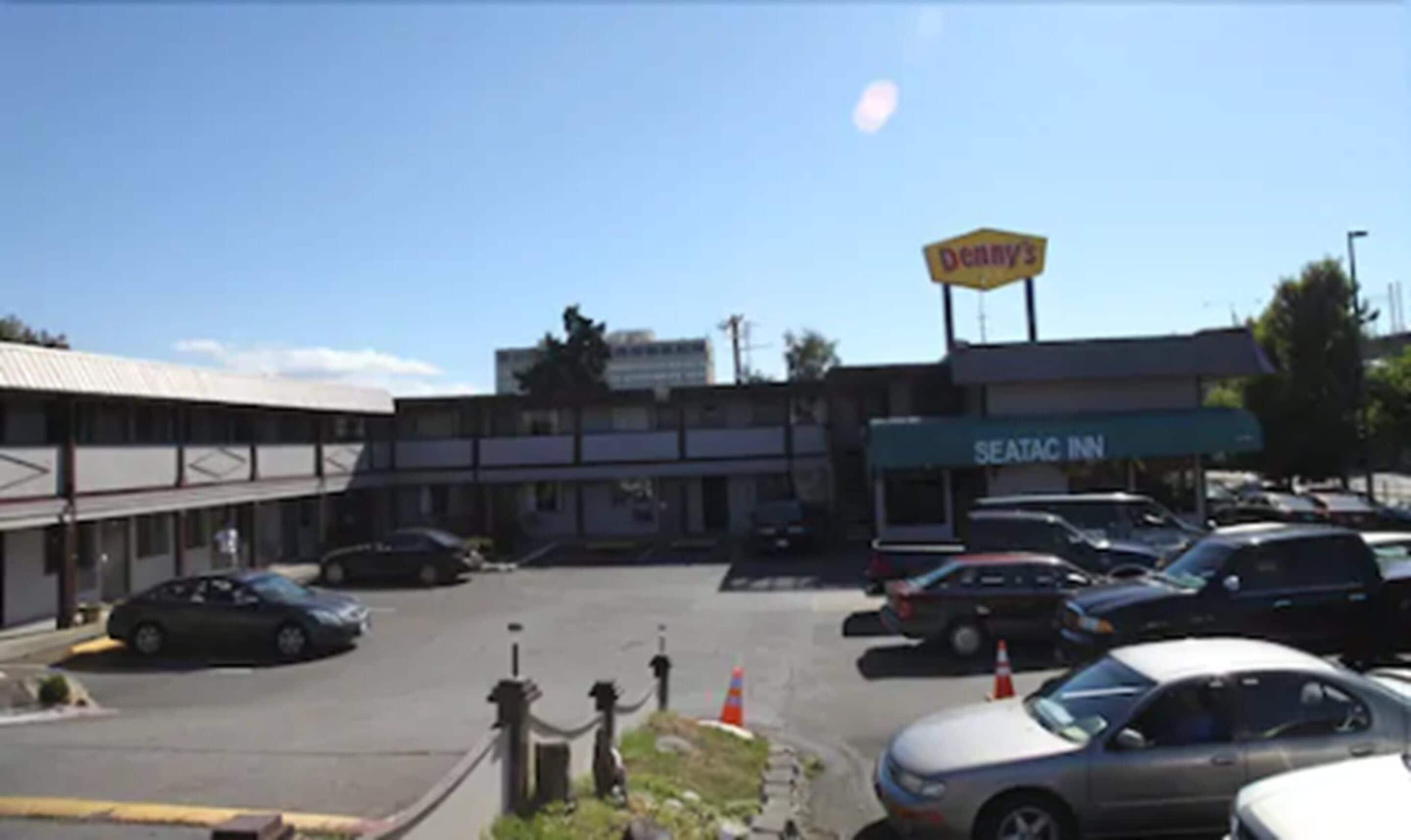 Un estacionamiento con automóviles, un letrero que dice 'Denny's' y un edificio del 'Seatac Inn'.